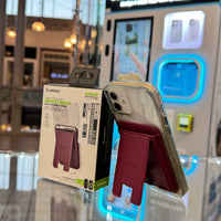 Digital photograph of an ESSOULK magnetic maroon wallet phone stand attached to a clear-cased iPhone, displayed with its $10.00 packaging on a glass counter in front of a blue-glowing CUSTOM CASE KIOSK