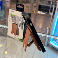 Photograph of an Esoulk brown leatherette magnetic wallet and foldable stand attached to a dark phone, displayed on a glass retail counter with its product packaging showing a $10 price sticker