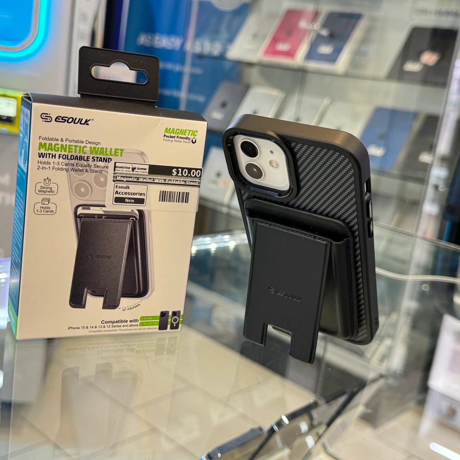 An Esoulk magnetic wallet with foldable stand is shown attached to an iPhone featuring a black carbon fiber textured case, displayed on a glass counter in a retail store highlighting green product text and a $10.00 price
