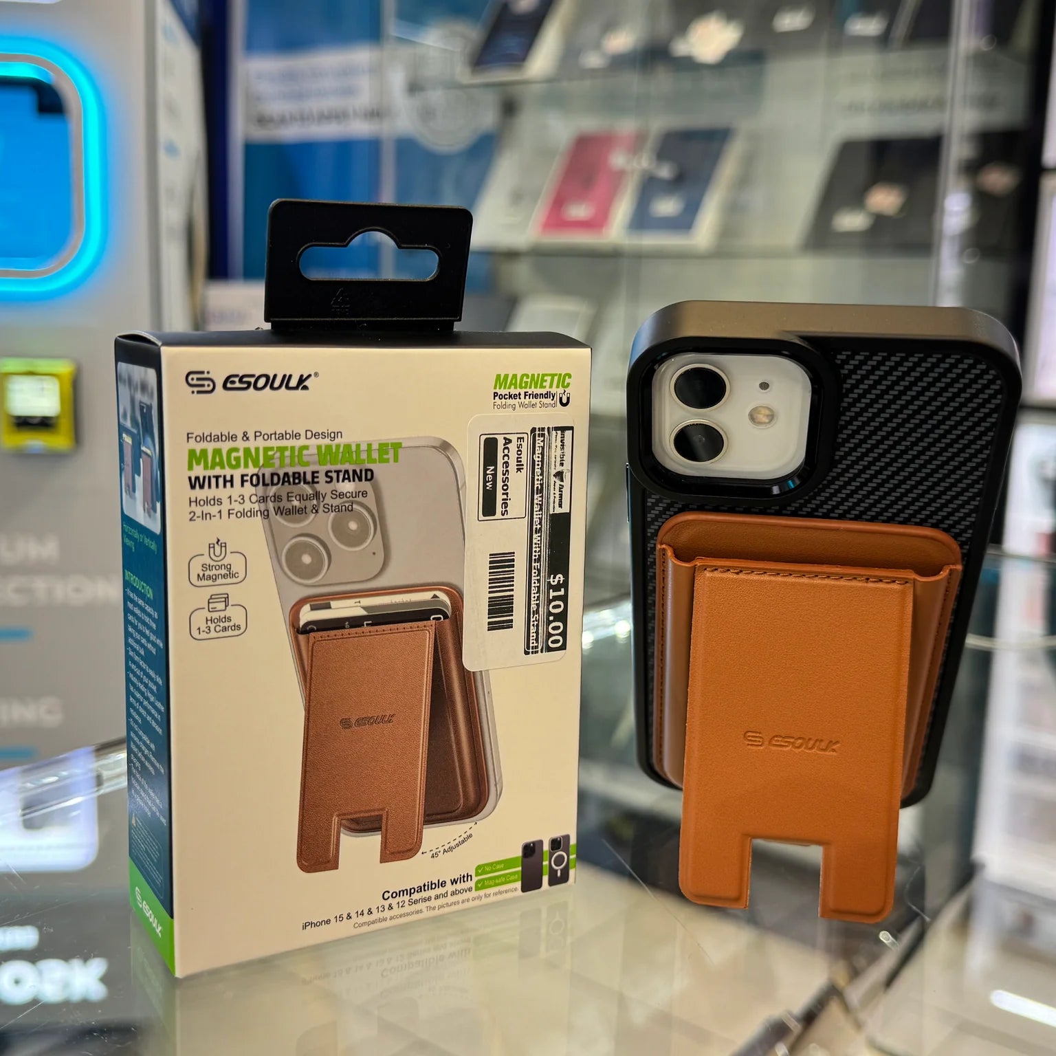 An ESOUK tan magnetic wallet with a foldable stand attached to a black carbon fiber iPhone case, displayed next to its $10.00 retail packaging against a blurred background with a bright blue glowing sign